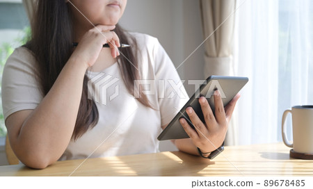 Thoughtful young woman using digital tablet, surfing internet at home. Thoughtful young woman using digital tablet, surfing internet at home. 89678485
