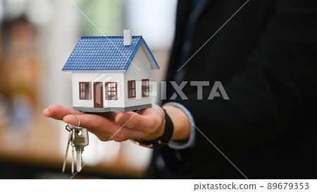 Businessman hand holding house model and house keys. New house, insurance and real estate concept. Businessman hand holding house model and house keys. New house, insurance and real estate concept. 89679353