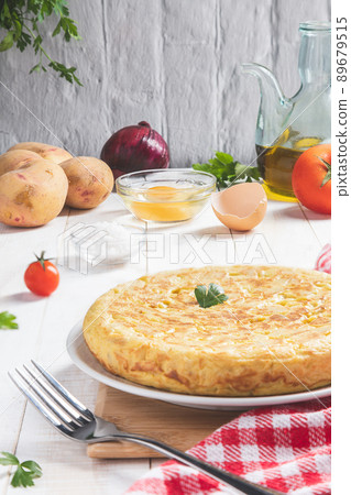 Traditional Spanish omelette with potatoes and onion with ingredients on a light rustic background, vertical format. Spanish tapas. Traditional Spanish omelette with potatoes and onion with ingredients on a light rustic background, vertical format. Spanish tapas. 89679515