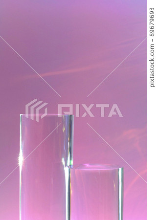 two clear glass cylinder podiums on pastel pink background  89679693
