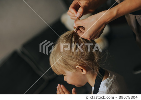 Mom makes a ponytail for a little daughter. Mom makes a ponytail for a little daughter. 89679804