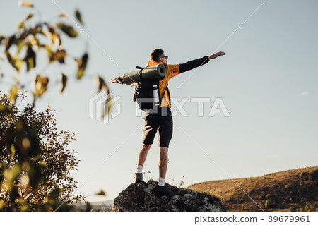 Back View of Travel Man with Backpack, Standing on the Top of Rock During Sunset, Male Nomad Enjoy Freedom, Solo Trip Concept Back View of Travel Man with Backpack, Standing on the Top of Rock During Sunset, Male Nomad Enjoy Freedom, Solo Trip Concept 89679961