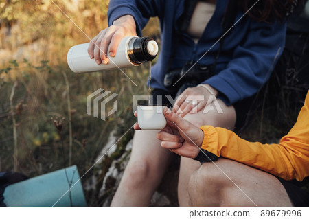 Two Travelers Man and Woman Made a Stop During the Hike to Drink Hot Tea from the Thermos 89679996