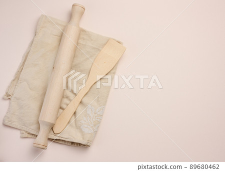 Wooden rolling pin for rolling dough on a beige background, top view. Copy space 89680462