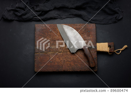 Rectangular empty wooden cutting board and kitchen knife on black table with gauze napkin, top view 89680474
