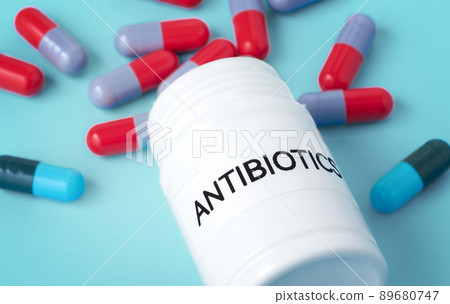 Antibiotic medicine concept, antibiotics bottle with pills spilled out, closeup on blue background 89680747