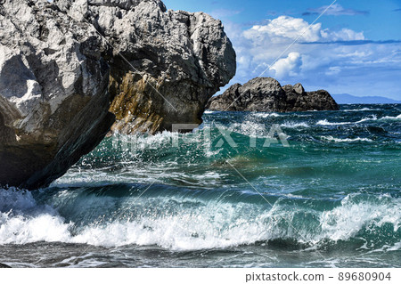 Blue sky, white clouds and waves crashing against the reef 89680904
