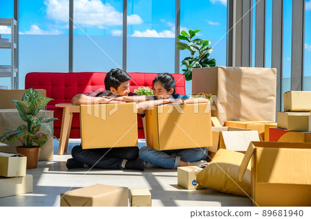 Young asian couple smiling, relaxing and resting on the floor after unpacking cardboard boxes in new house with cardboard boxes on floor 89681940