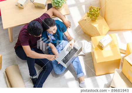 Top view of young asian couple working online shopping on laptop computer with cardboard parcel boxs of product for deliver at home. Start up online business concept Top view of young asian couple working online shopping on laptop computer with cardboard parcel boxs of product for deliver at home. Start up online business concept 89681943