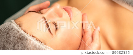 Facial massage. Hands of a masseur massaging neck of a young caucasian woman in a spa salon, the concept of health massage 89682525