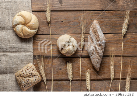 Bread with wheat ears and flour on wood board, top view. Bread with wheat ears and flour on wood board, top view. 89683188