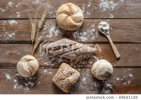 Bread with wheat ears and flour on wood board, top view. Bread with wheat ears and flour on wood board, top view. 89683189