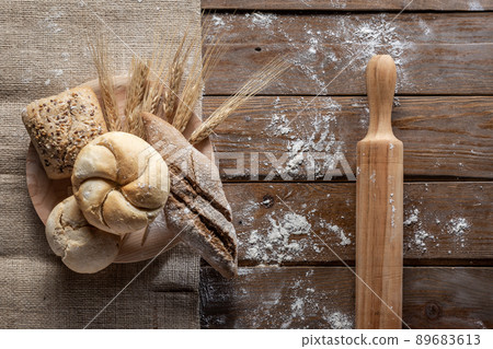 Bread with wheat ears and flour on wood board, top view 89683613