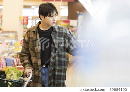 A young man shopping at a supermarket A young man shopping at a supermarket 89684100