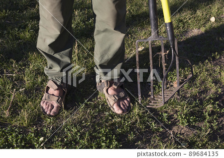 Man with rakes and pitchforks on background of garden Man with rakes and pitchforks on background of garden 89684135