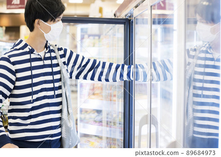 Young man buying frozen food in supermarket 89684973
