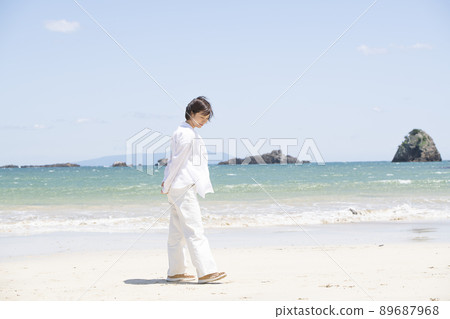 Young woman taking a walk on the beach Young woman taking a walk on the beach 89687968