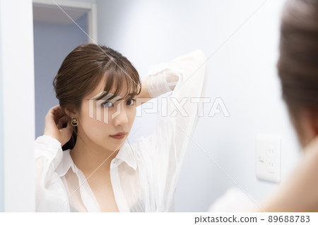 A woman doing a hair set in front of a mirror 89688783