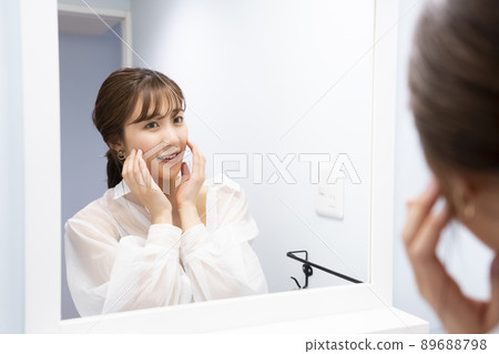 A woman checking her skin in the mirror A woman checking her skin in the mirror 89688798