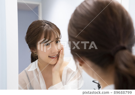 A woman checking her skin in the mirror A woman checking her skin in the mirror 89688799