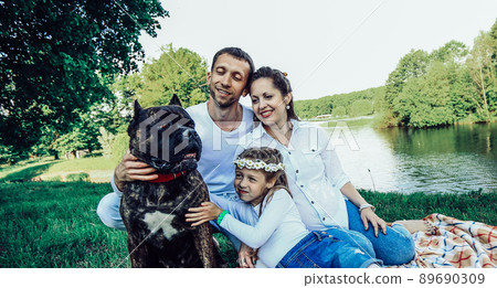 happy family with pet dog at picnic in a Sunny summer day. pregn 89690309