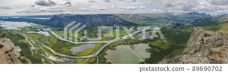 Aerial panoramic scenic view from Skierffe rock summit on glacial Rapadalen river delta valley at Sarek national park with meanders, lakes, mountains, birch trees. Summer day landscape Sweden Lapland 89690702