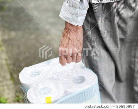 Hands of an elderly woman with a pack of toilet paper Hands of an elderly woman with a pack of toilet paper 89690997