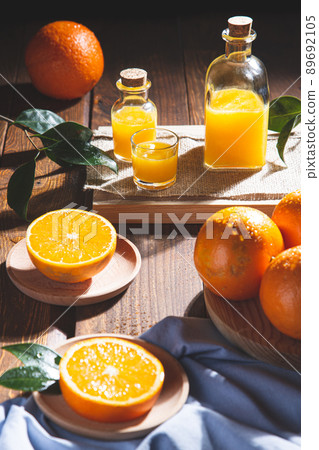 Oranges, oranges slices, orange leaves, and glass containers with orange juice on wooden background. 89692105