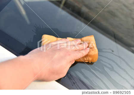 Washing a white car with a sponge by hand 89692505