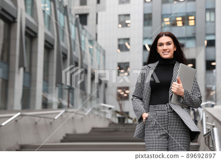 Beautiful woman in stylish suit with laptop outdoors. Space for text Beautiful woman in stylish suit with laptop outdoors. Space for text 89692897
