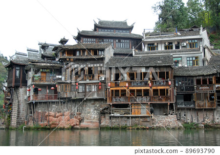 Fenghuang, Hunan Province, China: Old wooden riverside houses in Fenghuang ancient town. The town is built on the Tuojiang River and is home to Miao and Tujia minority peoples. Fenghuang, Hunan Province, China: Old wooden riverside houses in Fenghuang ancient town. The town is built on the Tuojiang River and is home to Miao and Tujia minority peoples. 89693790