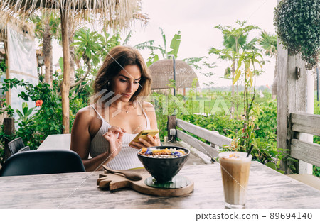 Focused ethnic woman watching smartphone on cafe terrace Focused ethnic woman watching smartphone on cafe terrace 89694140