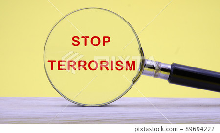 Stop Terrorism text on a yellow background through a magnifying glass Stop Terrorism text on a yellow background through a magnifying glass 89694222