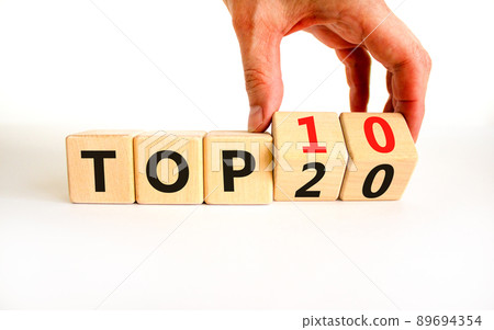 From Top 20 to 10 symbol. Businessman turns wooden cubes and changes concept words Top 20 to Top 10. Beautiful white table white background. Business and from Top 20 to Top 10 concept. Copy space. 89694354