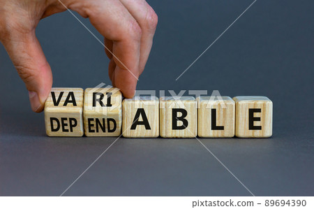 Dependable or variable symbol. Businessman turns wooden cubes and changes the word dependable to variable. Beautiful grey background, copy space. Business and dependable or variable concept. 89694390
