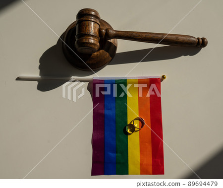 Legalization of same-sex marriages. Rainbow flag wedding rings and judge's gavel.  89694479