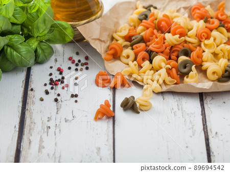 Raw homemade tricolore trottole pasta in brown paper on white wooden table background Raw homemade tricolore trottole pasta in brown paper on white wooden table background 89694542