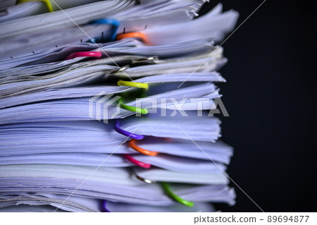 Multicolored paper clips on stack of paperwork Multicolored paper clips on stack of paperwork 89694877