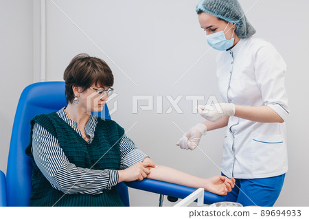 The patient takes a blood test at the clinic. The patient takes a blood test at the clinic. 89694933