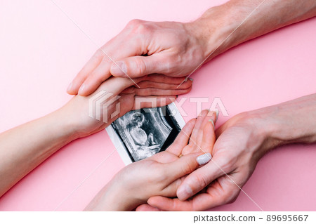 Ultrasound picture pregnant baby photo. Woman hands holding ultrasound pregnancy image on pink background. Concept of pregnancy, maternity, expectation for baby birth. Ultrasound picture pregnant baby photo. Woman hands holding ultrasound pregnancy image on pink background. Concept of pregnancy, maternity, expectation for baby birth. 89695667