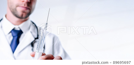 Syringe needle medical injection. Selective focus, doctor hand in blue gloves holding syringe with needle. Hospital white doctor gown, stethoscope. Syringe with flu vaccine with copy space. Syringe needle medical injection. Selective focus, doctor hand in blue gloves holding syringe with needle. Hospital white doctor gown, stethoscope. Syringe with flu vaccine with copy space. 89695697
