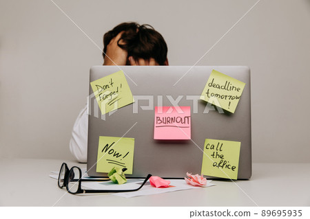 Worker have sticker pads on his laptop with tasks. Burnout theme Worker have sticker pads on his laptop with tasks. Burnout theme 89695935
