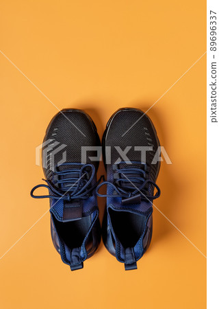 Pair of laced up mesh sneakers against orange background. Pair of laced up mesh sneakers against orange background. 89696337