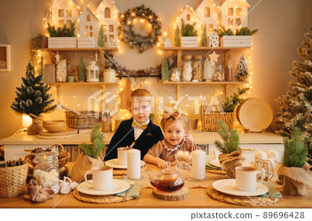 pretty little girl and boy at the kitchen table. christmas decor pretty little girl and boy at the kitchen table. christmas decor 89696428