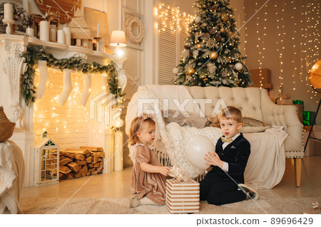 cute little girl and boy with a gift in a box on the floor of the room. new year cute little girl and boy with a gift in a box on the floor of the room. new year 89696429