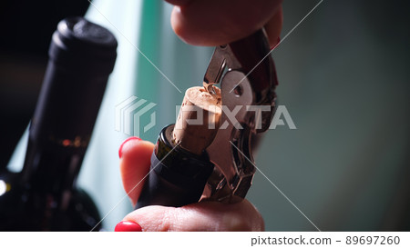 Opening bottle of wine in dark closeup Opening bottle of wine in dark closeup 89697260