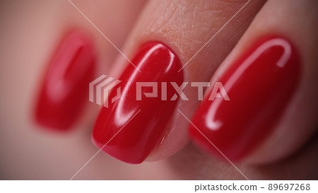 Red bright glossy nails on female nails closeup 89697268