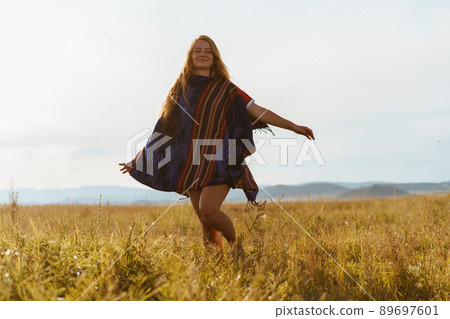Barefoot girl in striped cape with loose hair running across the field 89697601