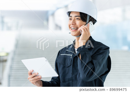 Young worker calling while looking at a tablet Young worker calling while looking at a tablet 89699475