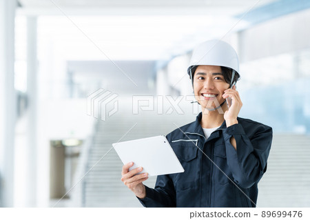 Young worker calling while looking at a tablet Young worker calling while looking at a tablet 89699476